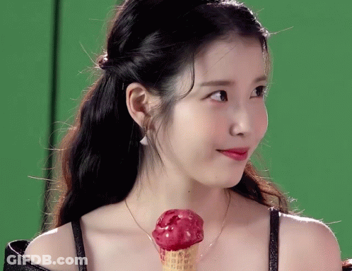 A Woman Is Holding A Red Ice Cream Cone In Her Hand GIF
