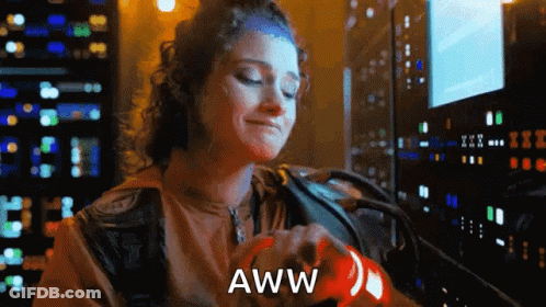 A Woman Is Holding A Red Object With The Word Aww Written On It . GIF