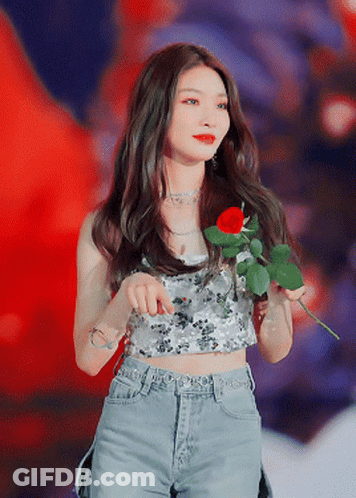 A Woman Is Holding A Red Rose In Her Hand GIF