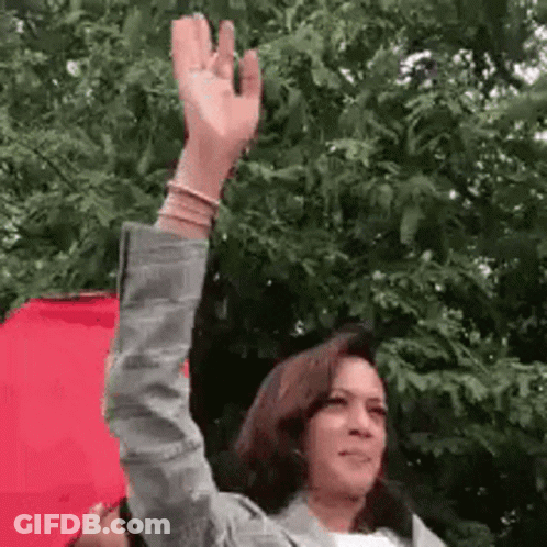 A Woman Is Holding A Red Umbrella And Waving Her Hand In The Air . GIF