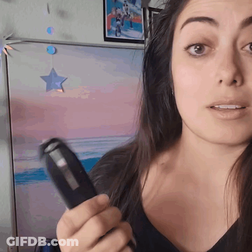 A Woman Is Holding A Remote Control In Front Of A Painting Of A Beach GIF