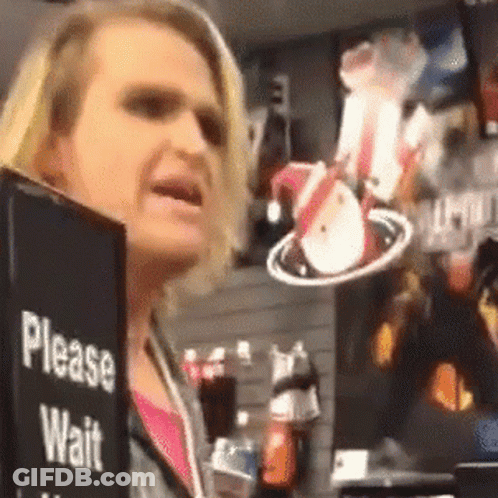 A Woman Is Holding A Sign That Says " Please Wait " GIF