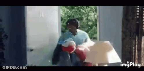 A Woman Is Holding A Stuffed Animal And A Lamp While Standing In Front Of A Doorway . GIF