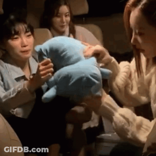 A Woman Is Holding A Stuffed Animal In Her Hands While Sitting In A Car . GIF