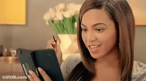 A Woman Is Holding A Tablet In Her Hand And Smiling . GIF