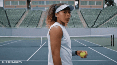 A Woman Is Holding A Tennis Ball On A Court GIF