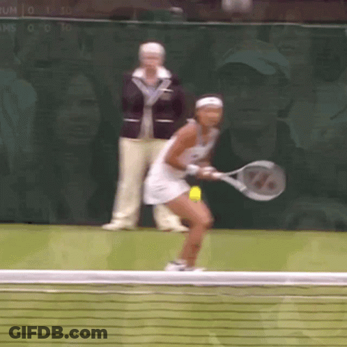 A Woman Is Holding A Tennis Racquet And Playing Tennis GIF