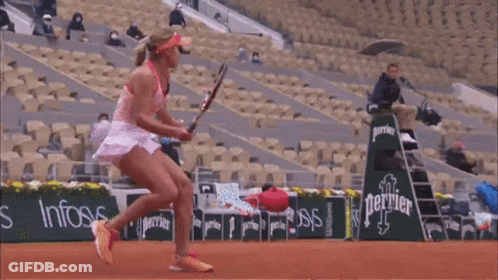 A Woman Is Holding A Tennis Racquet In Front Of An Emirates Fly Better Sign GIF