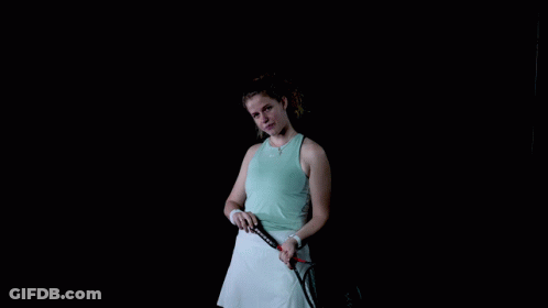 A Woman Is Holding A Tennis Racquet In Her Hand GIF