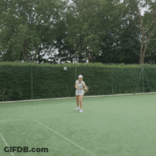 A Woman Is Holding A Tennis Racquet On A Court GIF