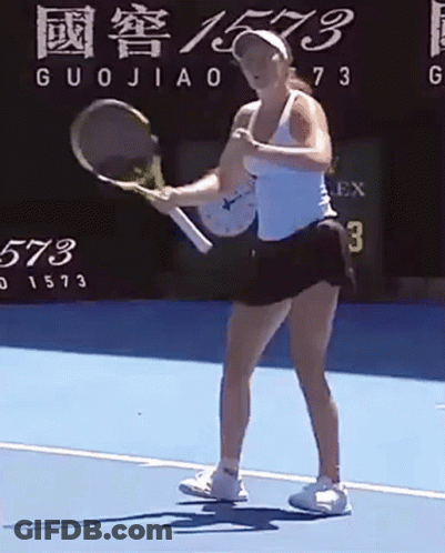 A Woman Is Holding A Tennis Racquet On A Tennis Court In Front Of A Scoreboard . GIF