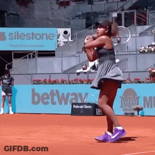 A Woman Is Holding A Tennis Racquet On A Tennis Court . GIF
