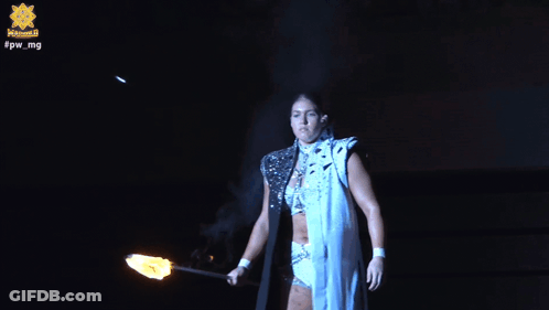 A Woman Is Holding A Torch In Front Of A Sign That Says Fpw Mg GIF