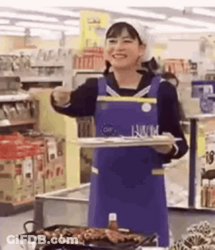 A Woman Is Holding A Tray Of Food In A Supermarket . GIF