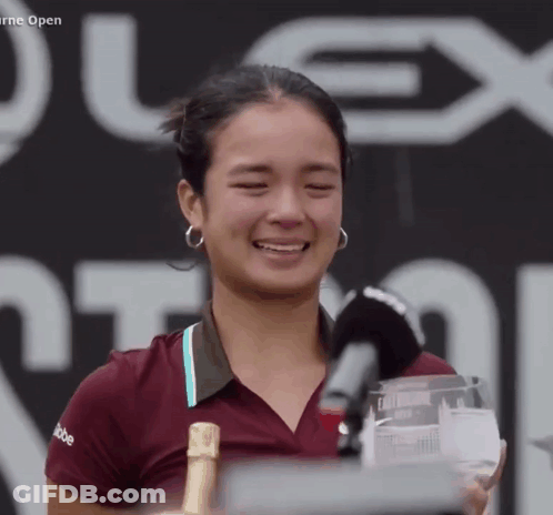 A Woman Is Holding A Trophy And A Bottle Of Champagne In Front Of A Sign That Says Plex Open GIF