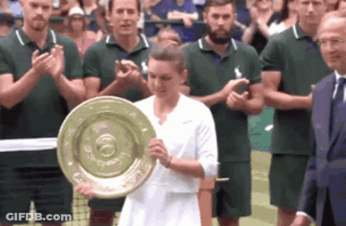 A Woman Is Holding A Trophy In Front Of A Crowd Of People GIF
