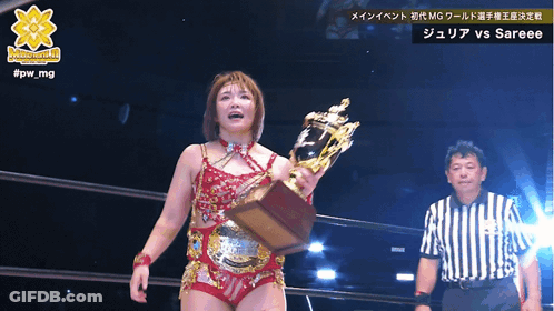 A Woman Is Holding A Trophy In Front Of A Referee And The Words #Jpw_mg Are Above Her GIF