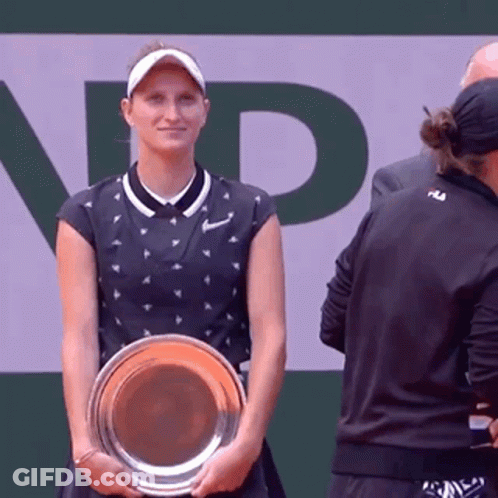 A Woman Is Holding A Trophy In Front Of A Sign That Says Np GIF
