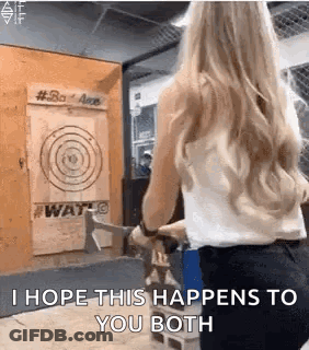 A Woman Is Holding An Axe In Front Of A Target And Says `` I Hope This Happens To You Both '' . GIF