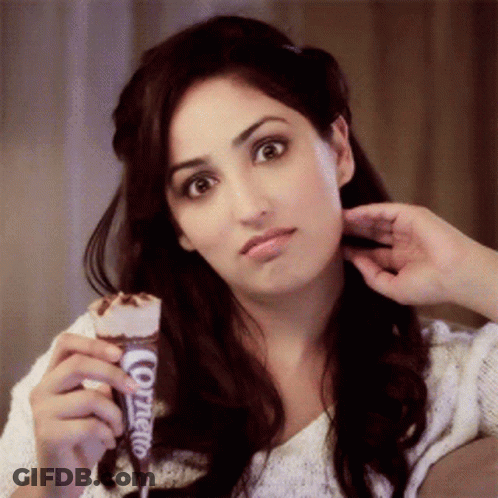 A Woman Is Holding An Ice Cream Cone That Says Cornetto On It GIF