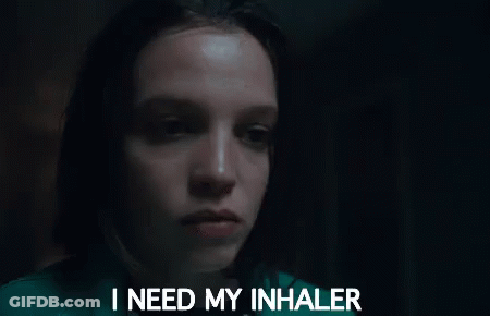 A Woman Is Holding An Inhaler In Her Hand In Front Of Her Face . GIF