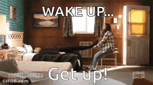 A Woman Is Holding Another Woman 'S Leg In A Room With The Words Wake Up Get Up Written On The Bottom GIF