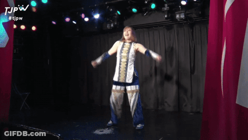 A Woman Is Holding Her Arms Up In The Air While Wearing A Scarf And Blue Gloves . GIF