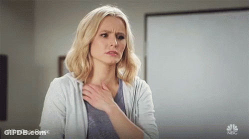 A Woman Is Holding Her Chest In Pain While Standing In A Classroom . GIF