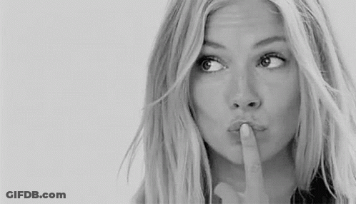 A Woman Is Holding Her Finger To Her Lips And Making A Shhh Gesture . GIF