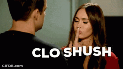 A Woman Is Holding Her Finger To Her Lips While A Man Looks On And The Words Clo Shush Are Above Her GIF