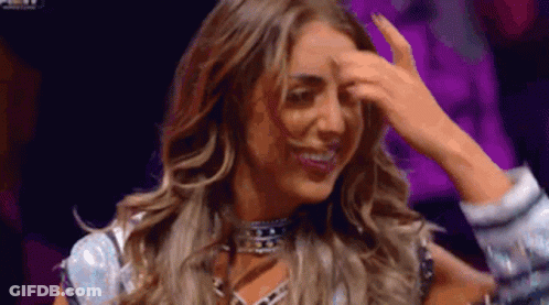 A Woman Is Holding Her Hand To Her Forehead . GIF