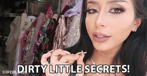 A Woman Is Holding Something In Her Hand In Front Of A Row Of Clothes And Says `` Dirty Little Secrets ! '' GIF