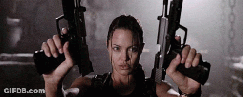 A Woman Is Holding Two Guns In Her Hands In A Dark Room GIF