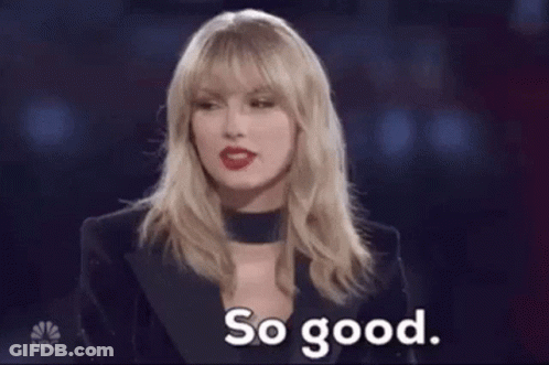 A Woman Is Holding Two Hot Dogs In A Pair Of Tongs And Saying So Good . GIF