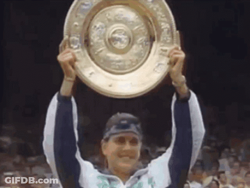 A Woman Is Holding Up A Trophy That Says ' Winner ' On It GIF