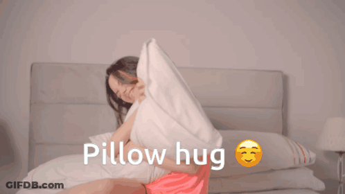 A Woman Is Hugging A Pillow With The Words Pillow Hug Written Below Her GIF