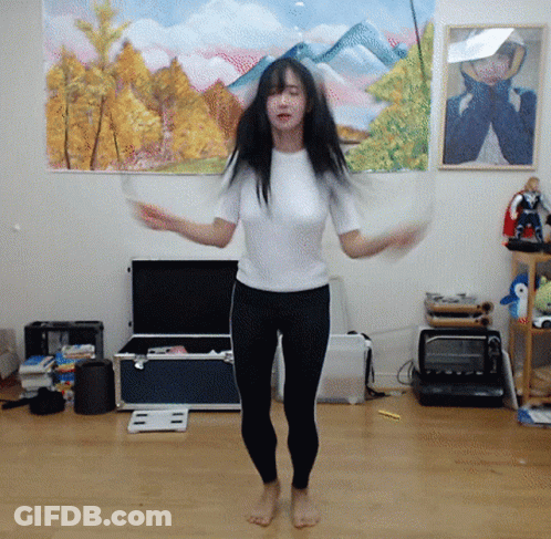 A Woman Is Jumping A Jump Rope In Front Of A Painting Of Mountains GIF