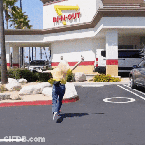 A Woman Is Jumping In Front Of An In N Out Restaurant GIF