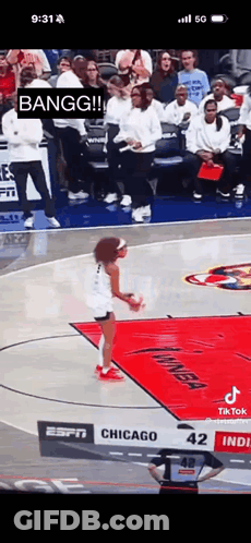 A Woman Is Jumping In The Air On A Basketball Court While A Crowd Watches . GIF