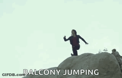 A Woman Is Jumping Off A Rock While A Man Watches . GIF