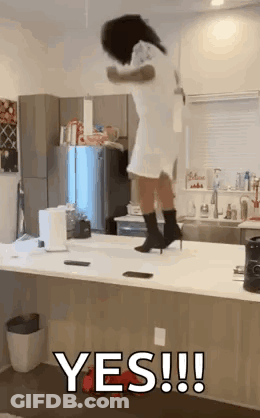 A Woman Is Jumping Over A Counter In A Kitchen While Wearing Heels . GIF
