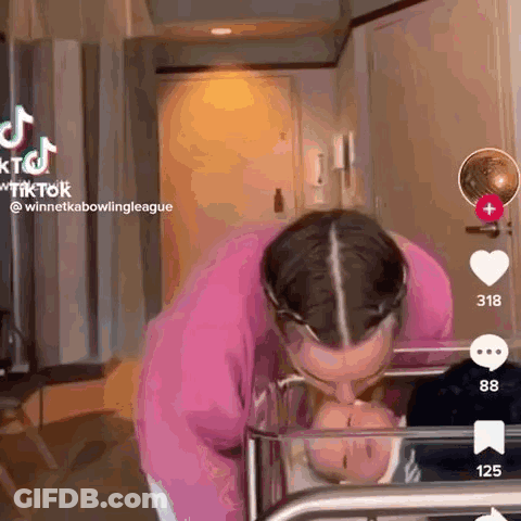 A Woman Is Kissing A Baby In A Crib In A Room . GIF