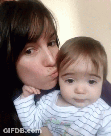 A Woman Is Kissing A Baby On The Cheek And The Baby Is Wearing A Striped Shirt GIF