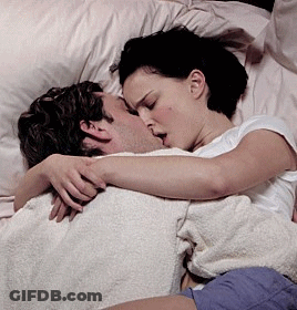 A Woman Is Kissing A Man In Bed GIF