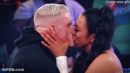 A Woman Is Kissing A Man On The Cheek In A Wrestling Match GIF