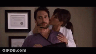 A Woman Is Kissing A Man On The Cheek While Holding His Neck . GIF