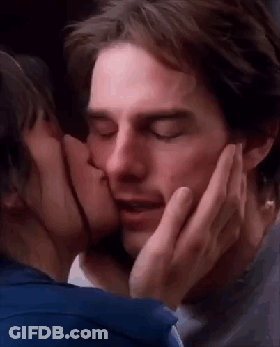A Woman Is Kissing A Man On The Cheek With Her Hand . GIF