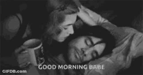 A Woman Is Kissing A Man On The Forehead While He Sleeps In Bed . GIF