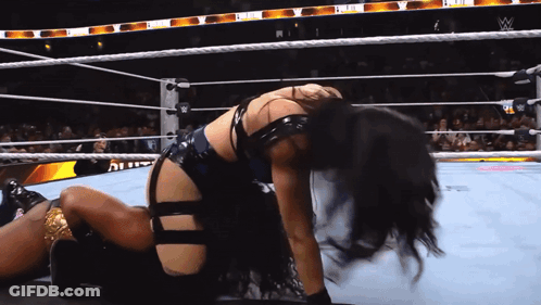 A Woman Is Kneeling Down In A Wrestling Ring With The W Logo On The Ropes GIF