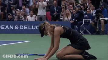 A Woman Is Kneeling Down On A Tennis Court In Front Of A Banner That Says Bean & Deluca GIF